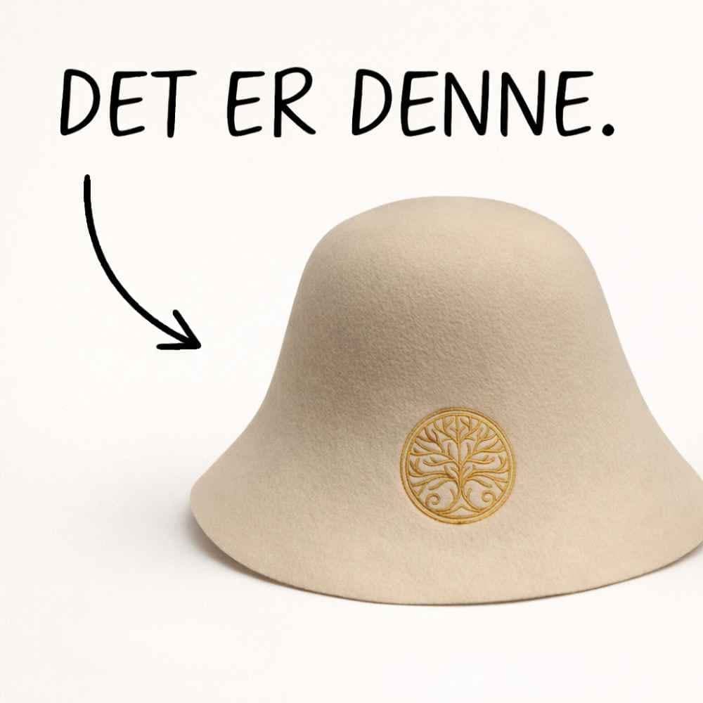 Annonse: en lys badstuehatt med gullbrodert livstre, med en håndtegnet pil og teksten «DET ER DENNE».
